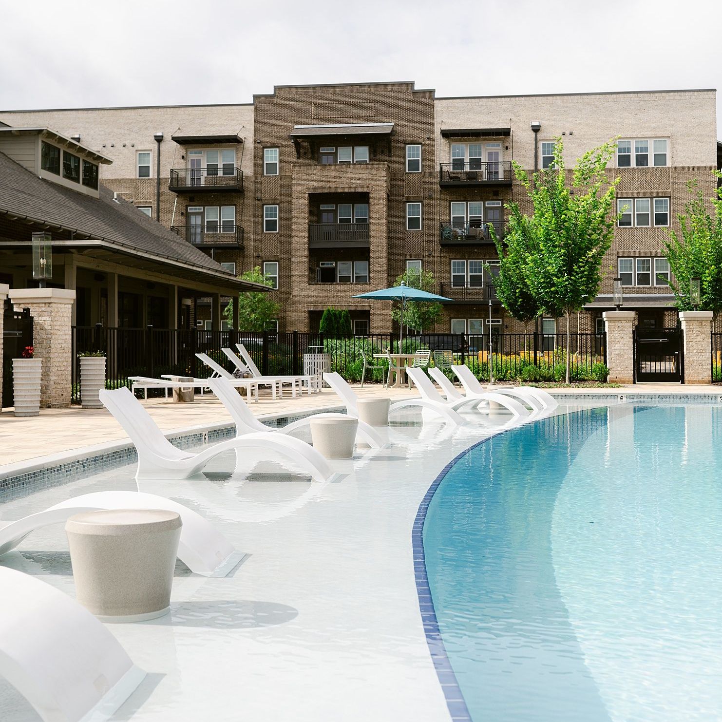 Three women are sitting at a table under an umbrella drinking wine.