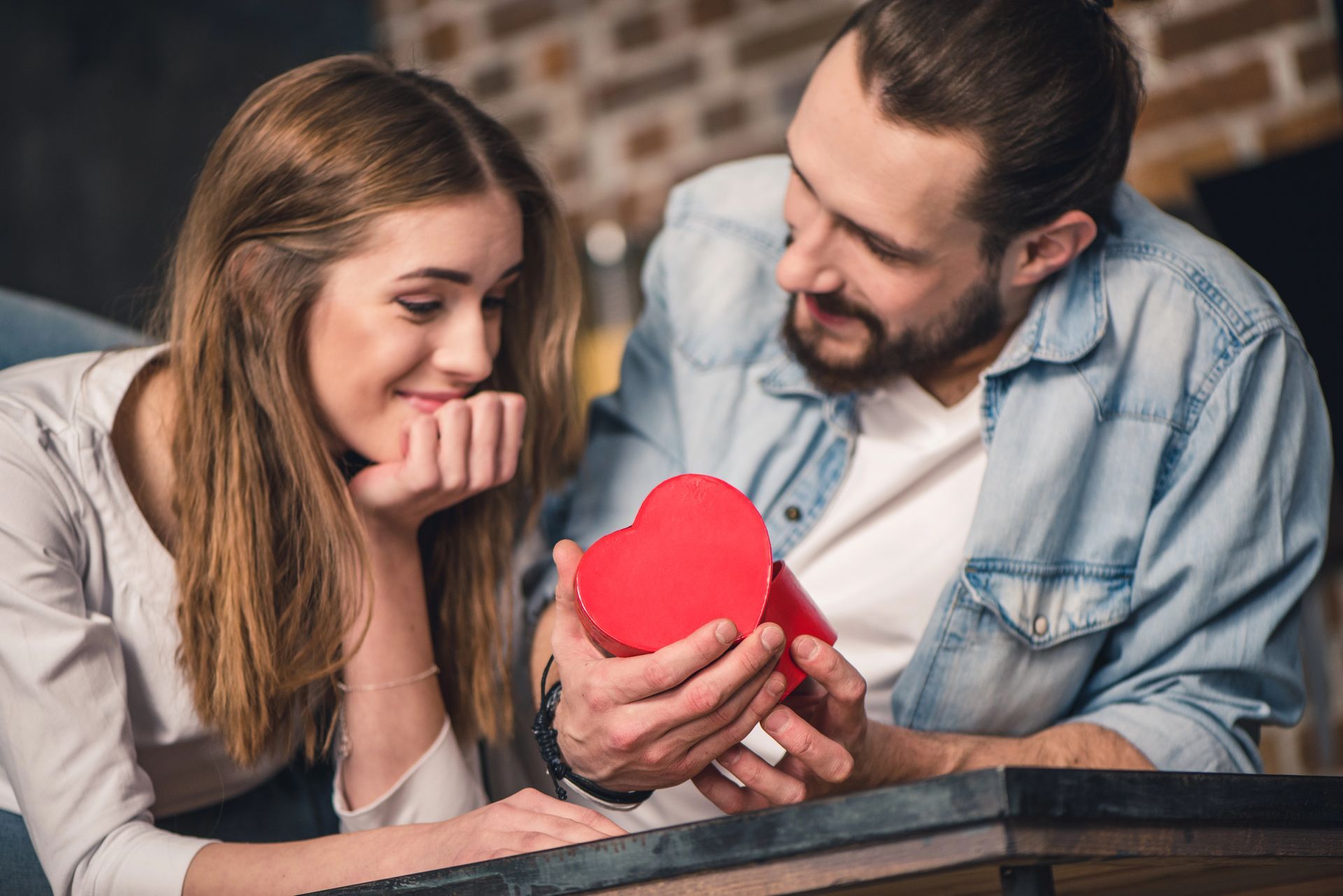 A man is giving a red heart to a woman.