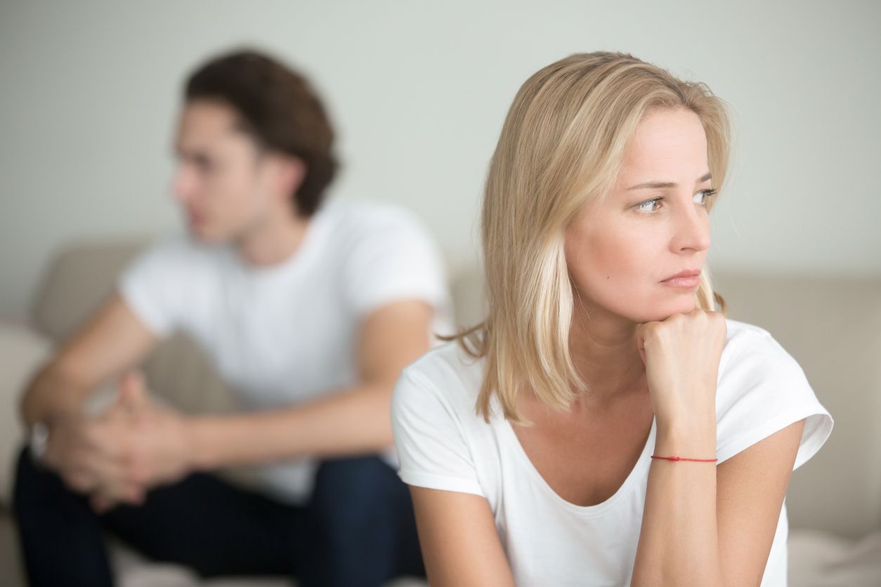 A man and a woman are sitting on a couch looking away from each other