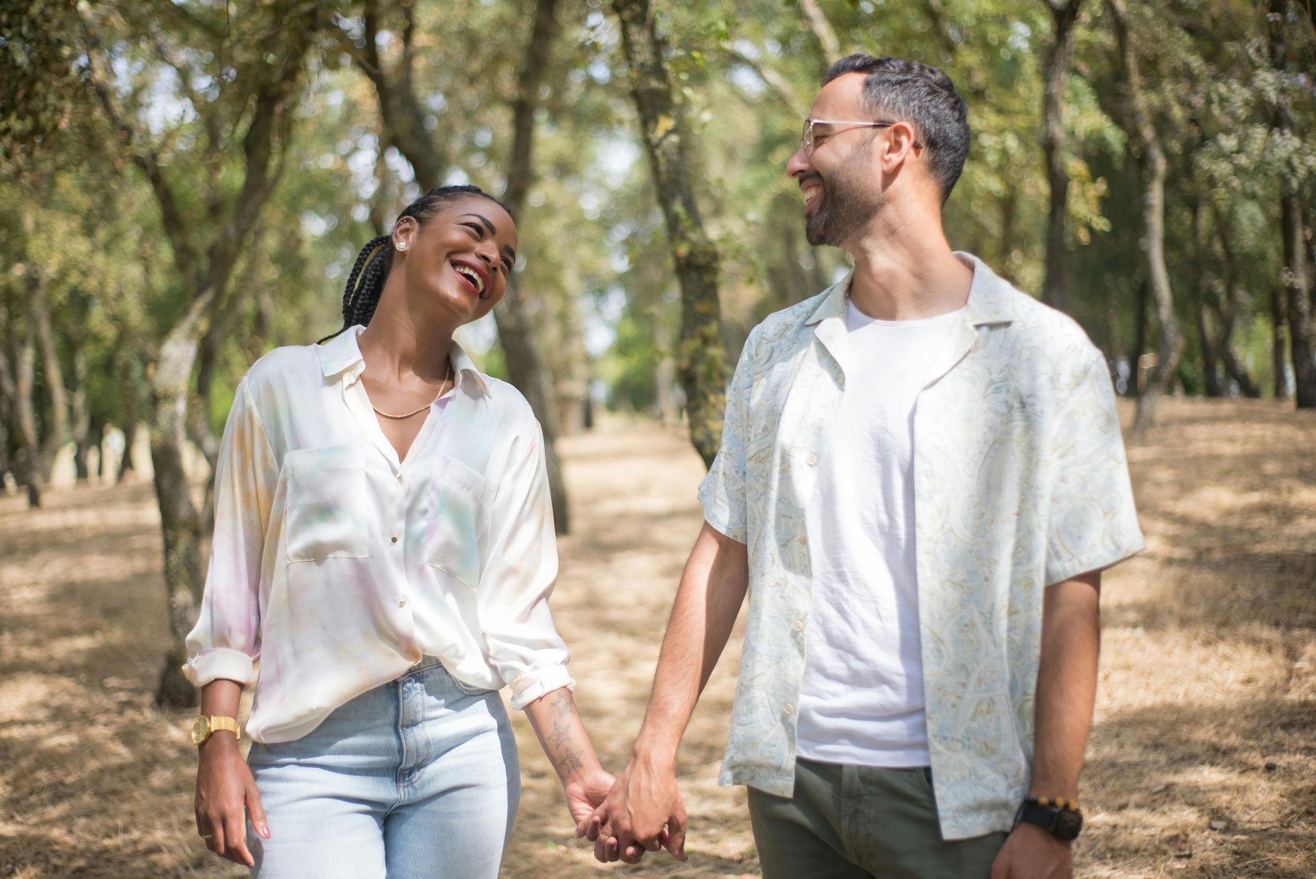 A man and a woman are holding hands in a park.
