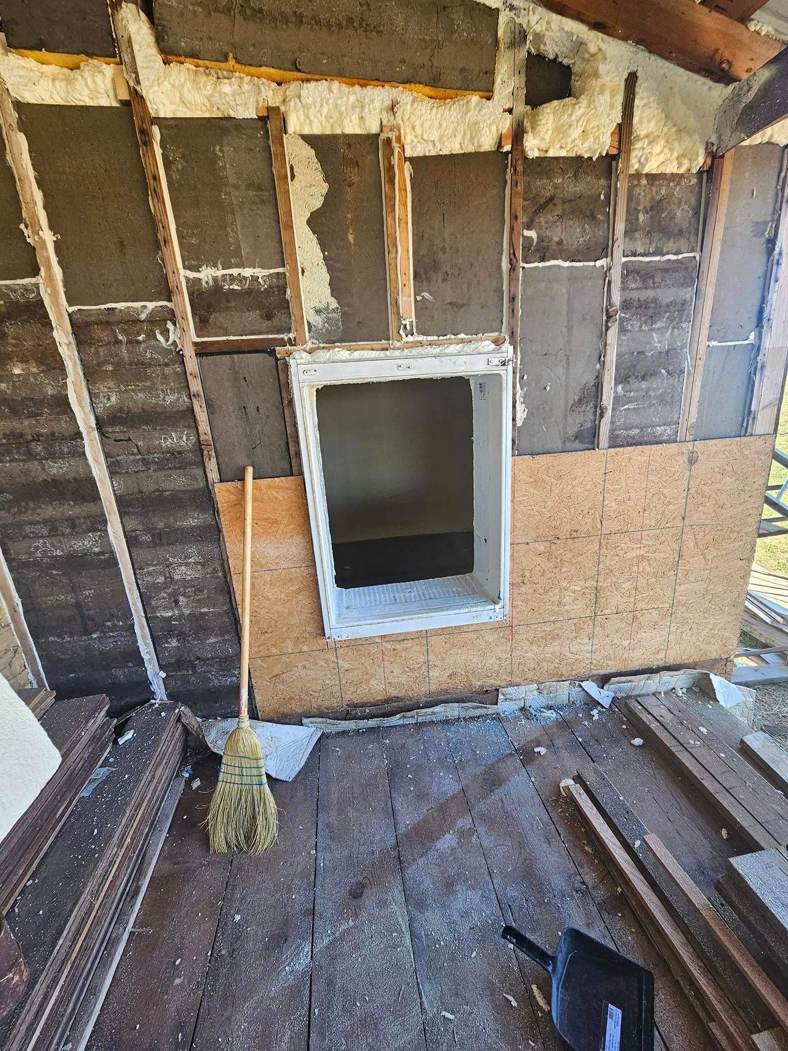 Interior wall under construction, partially exposed framing and a window opening.