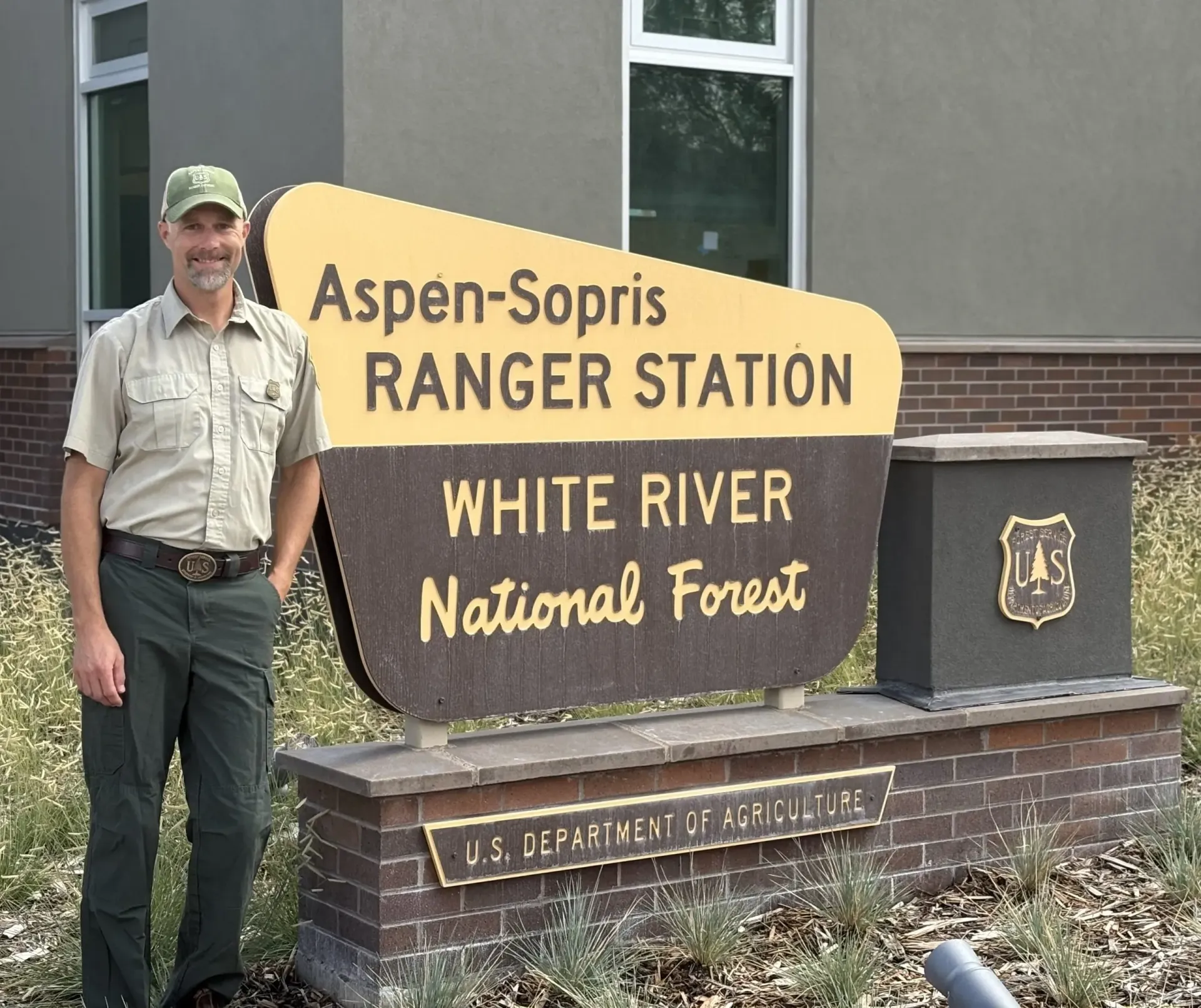 ranger standing in front of an aspen-sopris ranger station sign