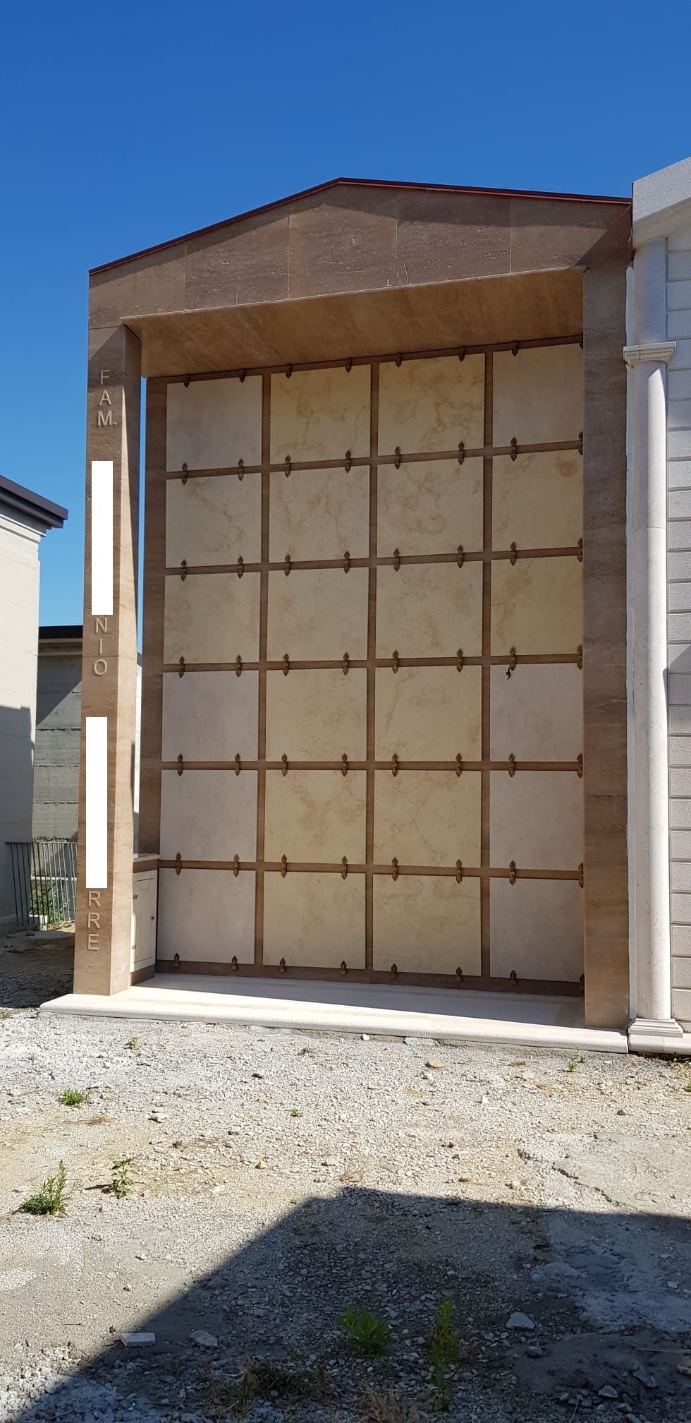 Esterno di una casa parzialmente finita, con struttura a vista e tetto marrone sotto un cielo azzurro limpido.