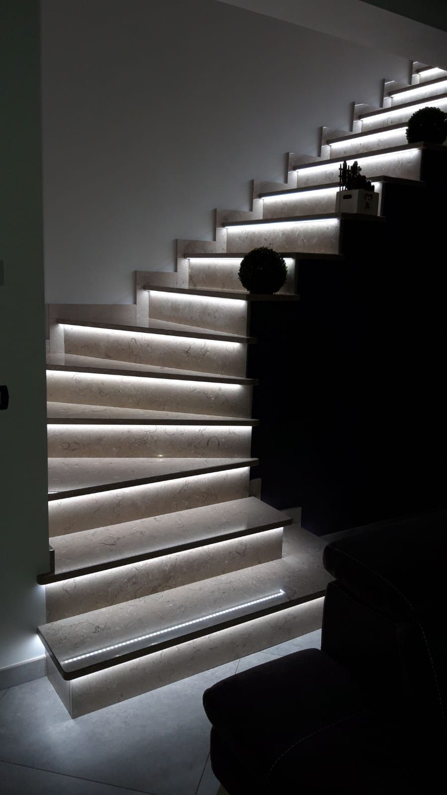 Scala moderna illuminata con gradini a luce bianca su una parete interna scura