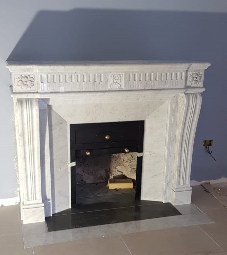 Camino decorativo bianco con mensola grigio scuro in una stanza con pareti grigio-blu.
