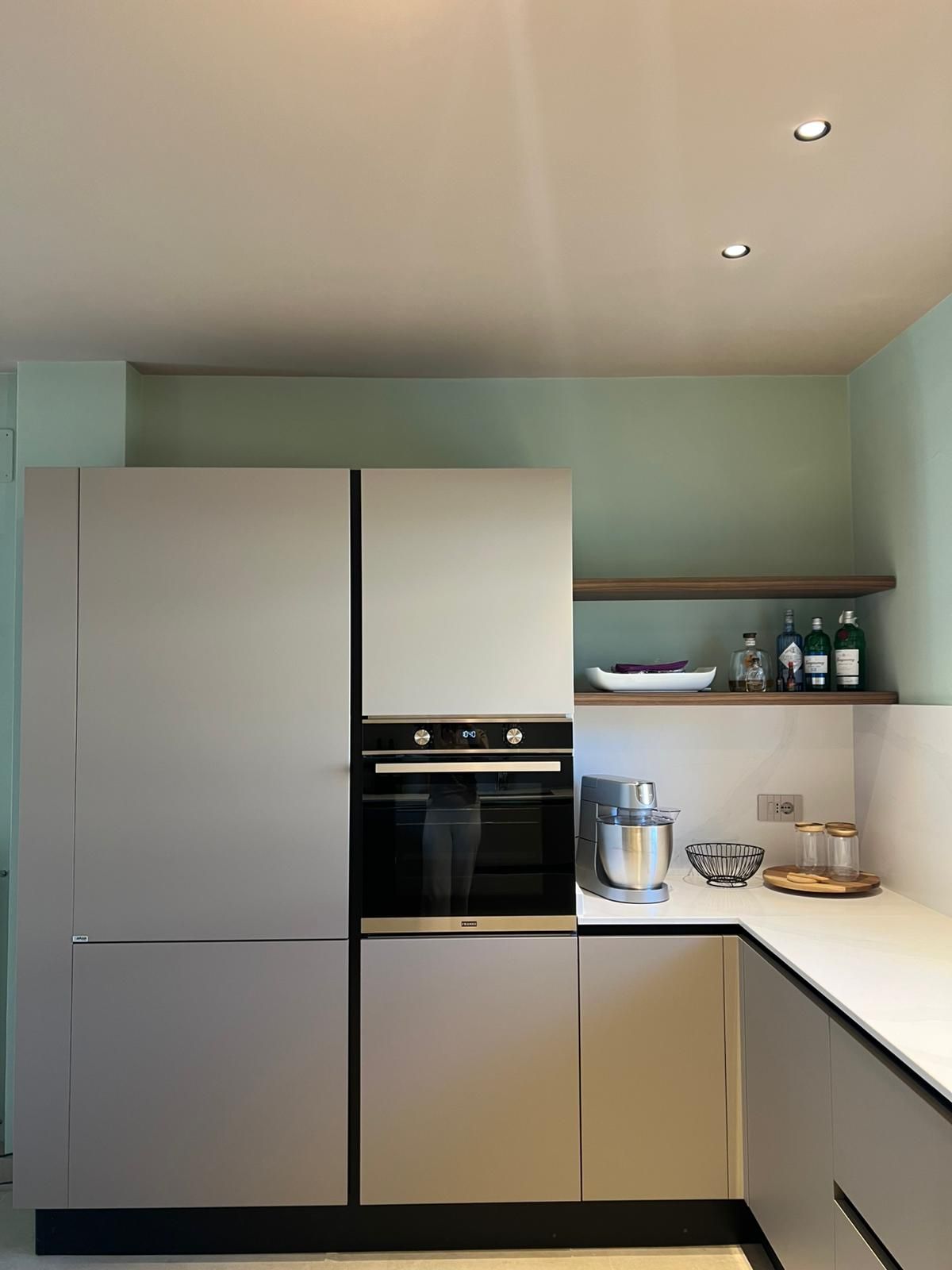 Cucina moderna e minimalista con mobili grigi, ripiani bianchi e mensole a vista.