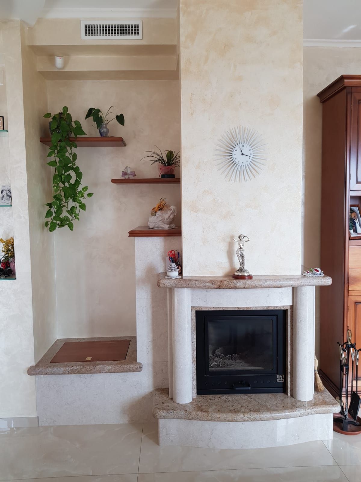 Camino del soggiorno con mensole a muro, pianta in vaso e rivestimento in pietra beige.