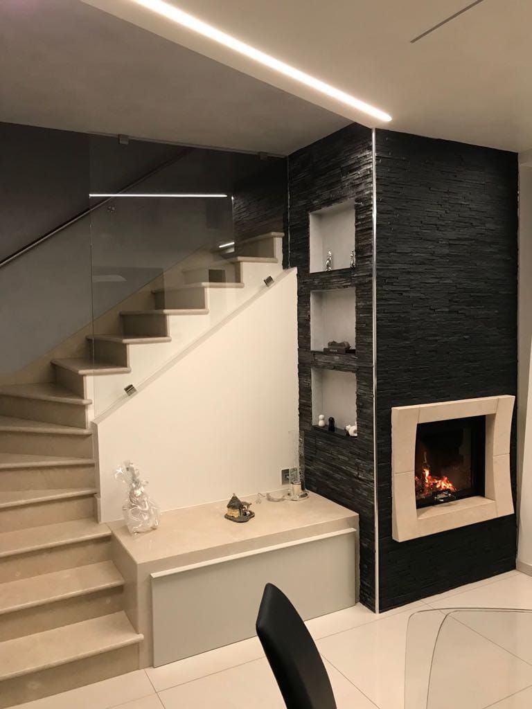 Scala moderna con gradini bianchi, parete decorativa nera, camino integrato e nicchia con mensola in un interno elegante