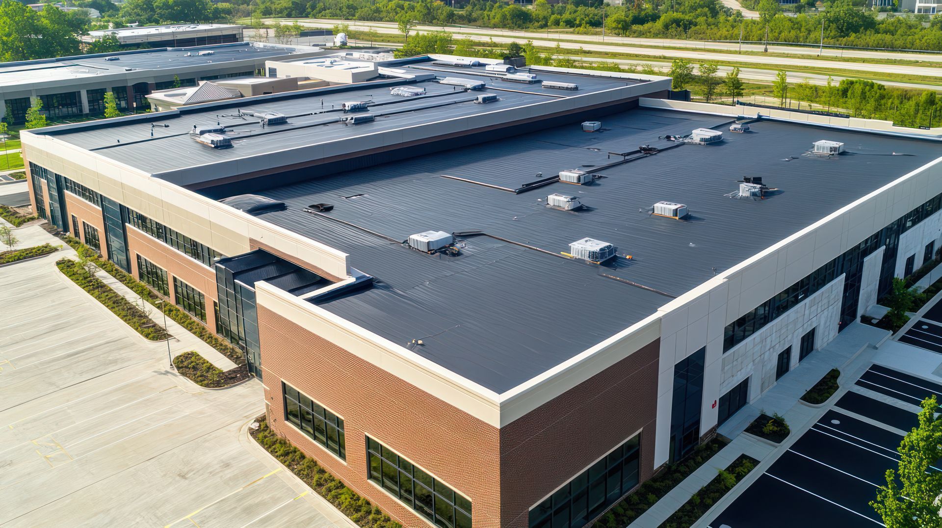 Aerial view of a large commercial building with a flat roof and parking lot. Aerial view of a large commercial building with a flat roof and parking lot.