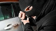 A man in a mask is trying to break into a car.