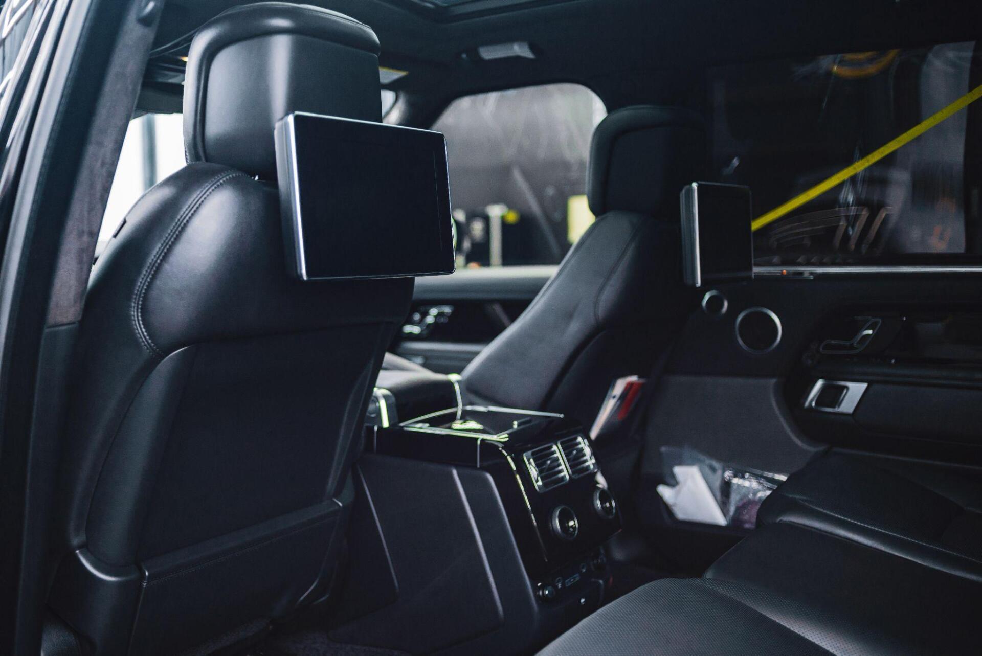 The back seat of a car with two headrest monitors.