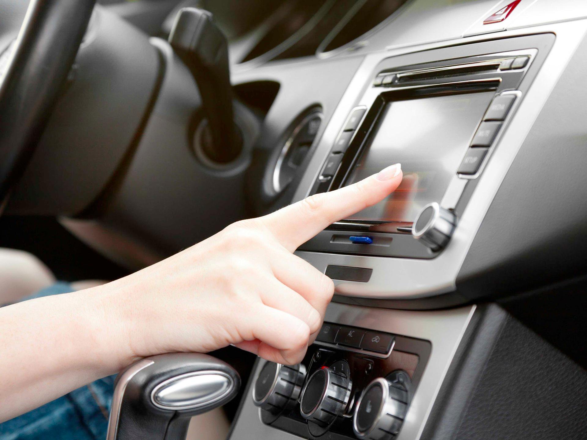 A person is pressing a button on a car radio