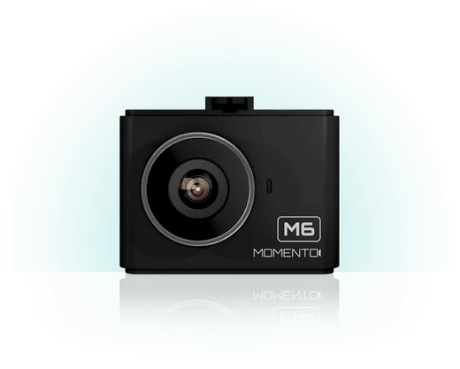 A black momento camera is sitting on a white surface.
