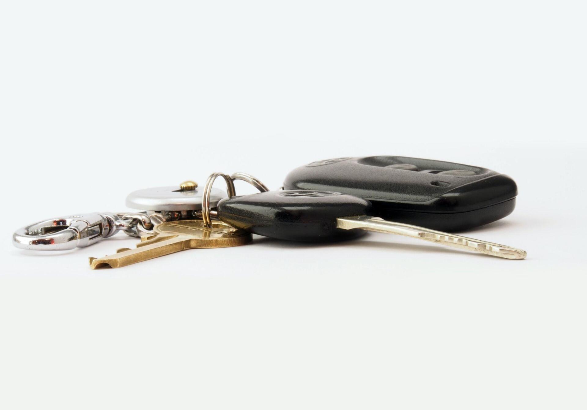 A bunch of car keys are sitting on top of each other on a white surface.