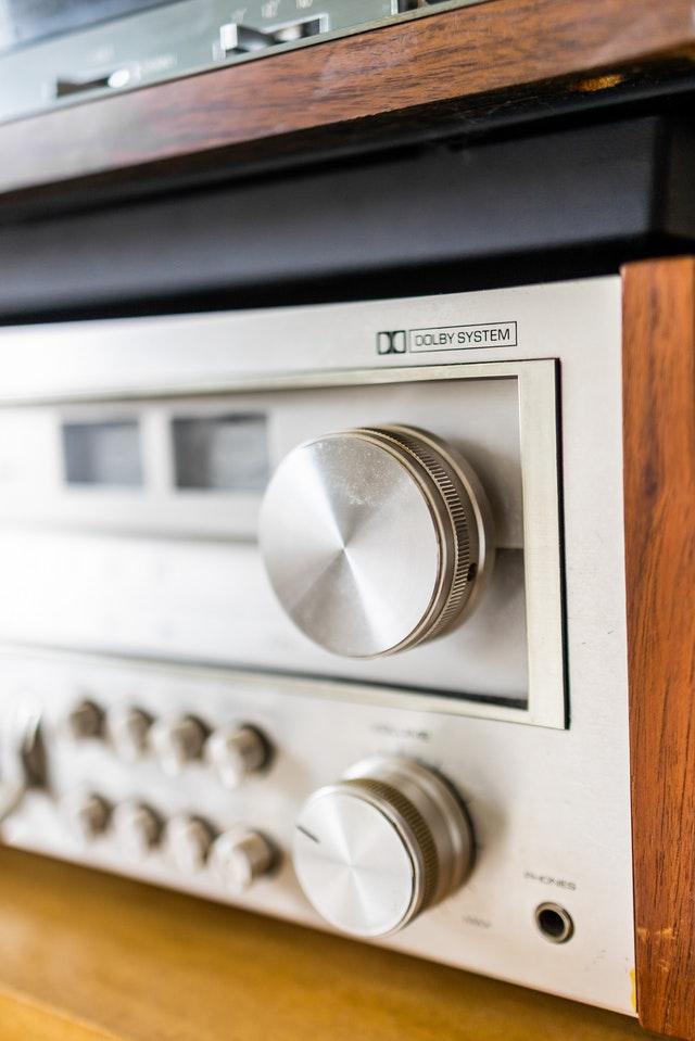 A close up of a stereo amplifier on a wooden shelf.