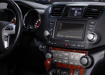 The interior of a car with a steering wheel and a radio.