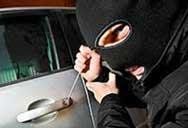 A man in a mask is trying to break into a car.