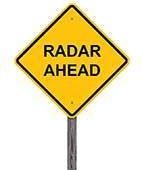 A yellow sign that says radar ahead on a pole.