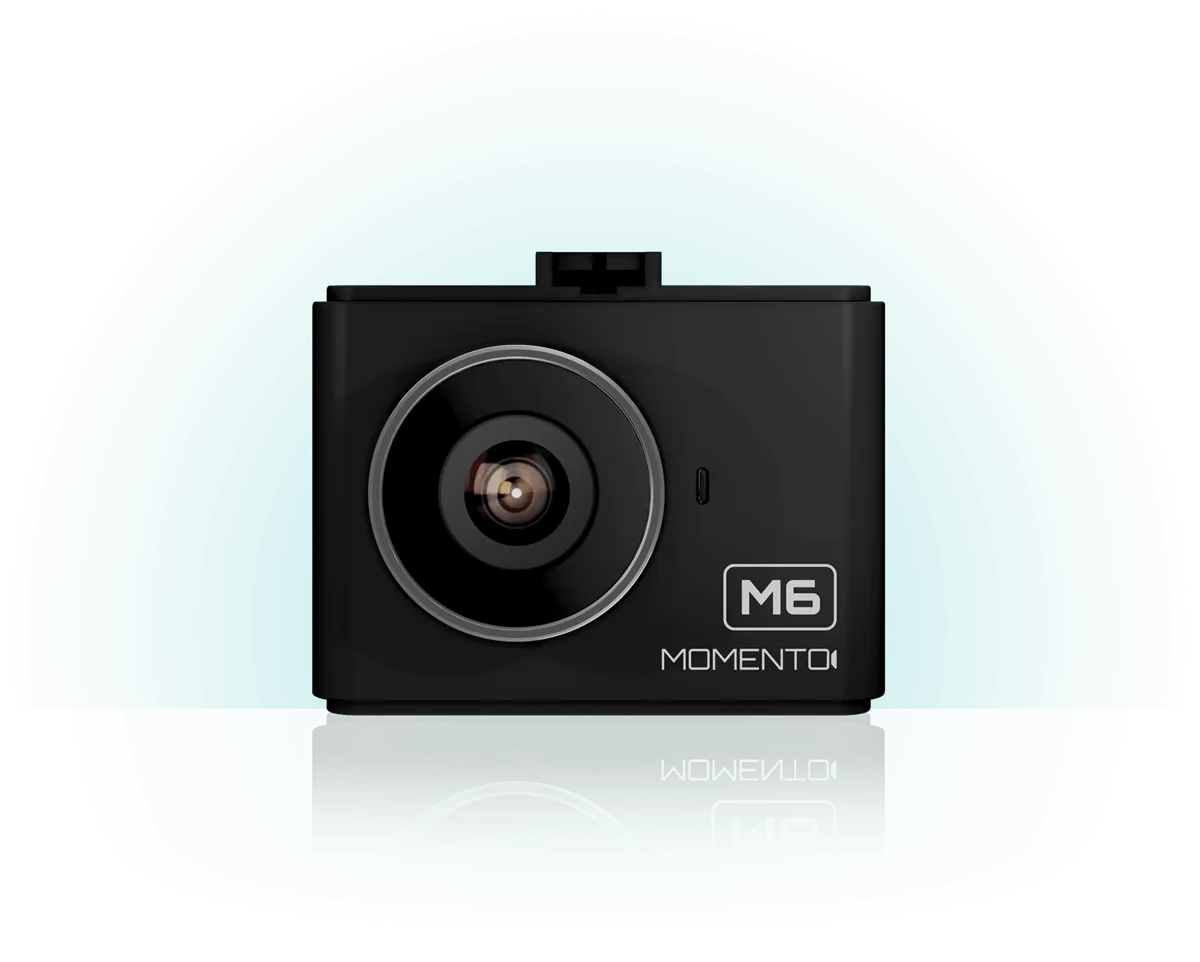 Black MomentCam M6 dashcam with a prominent lens, mounted on a white surface, with a light blue gradient background.