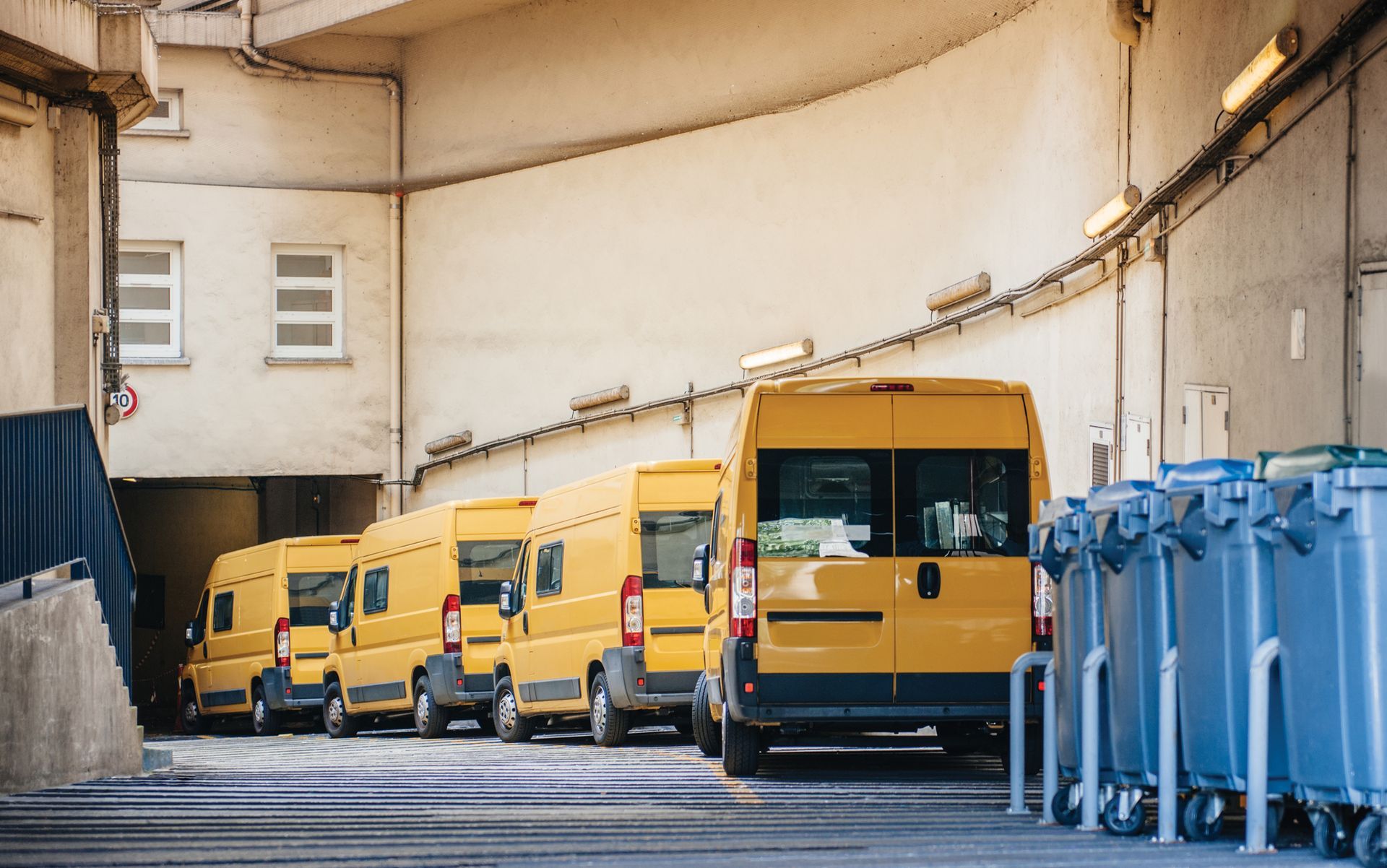 A row of yellow vans are parked in a parking garage.