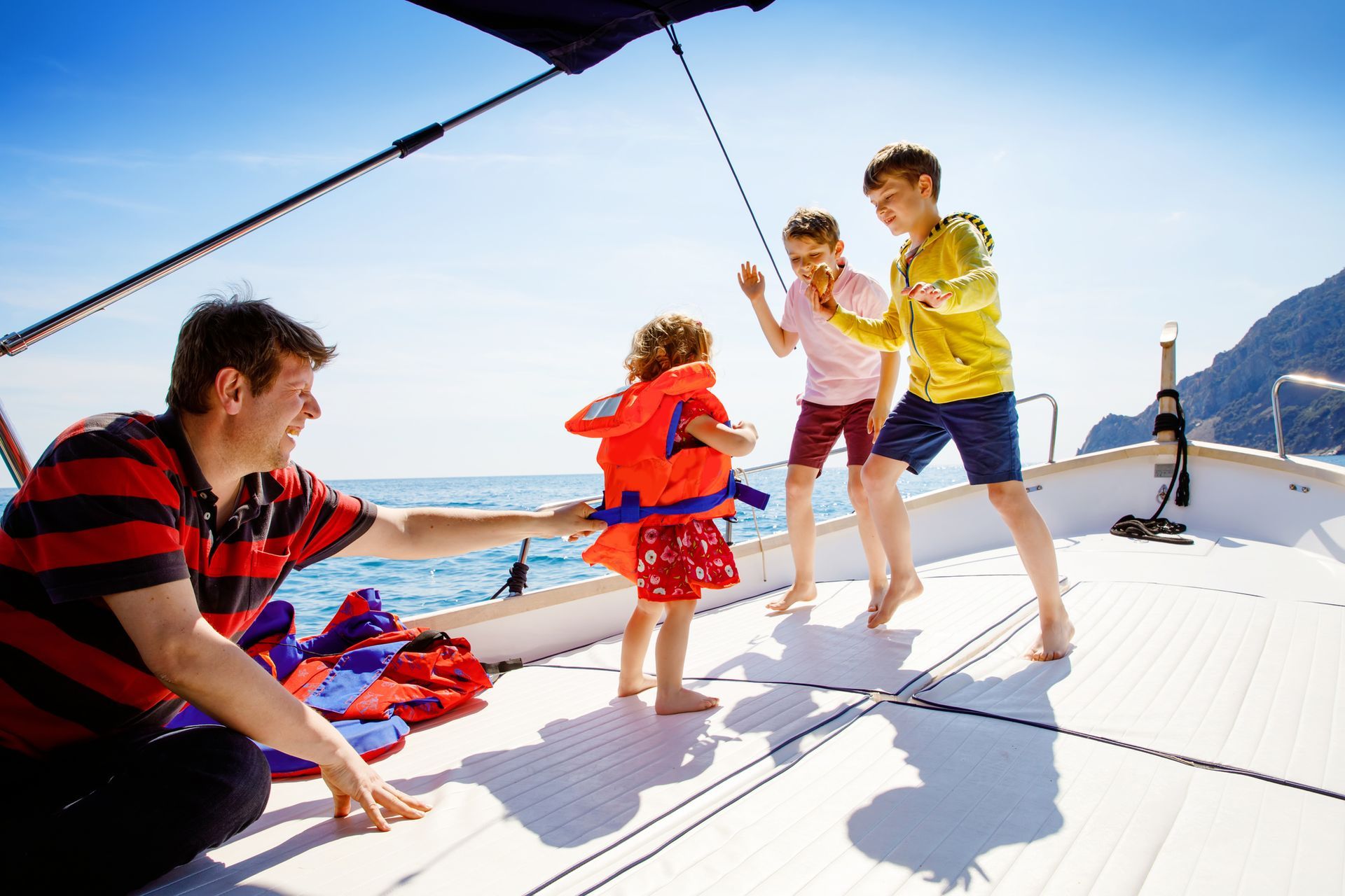 A man and three children are playing on a boat.