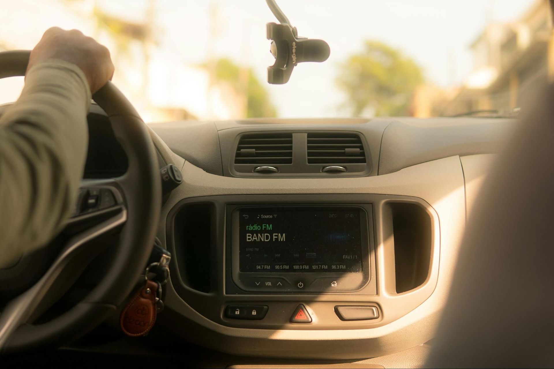 A person is driving a car with a radio on the dashboard.