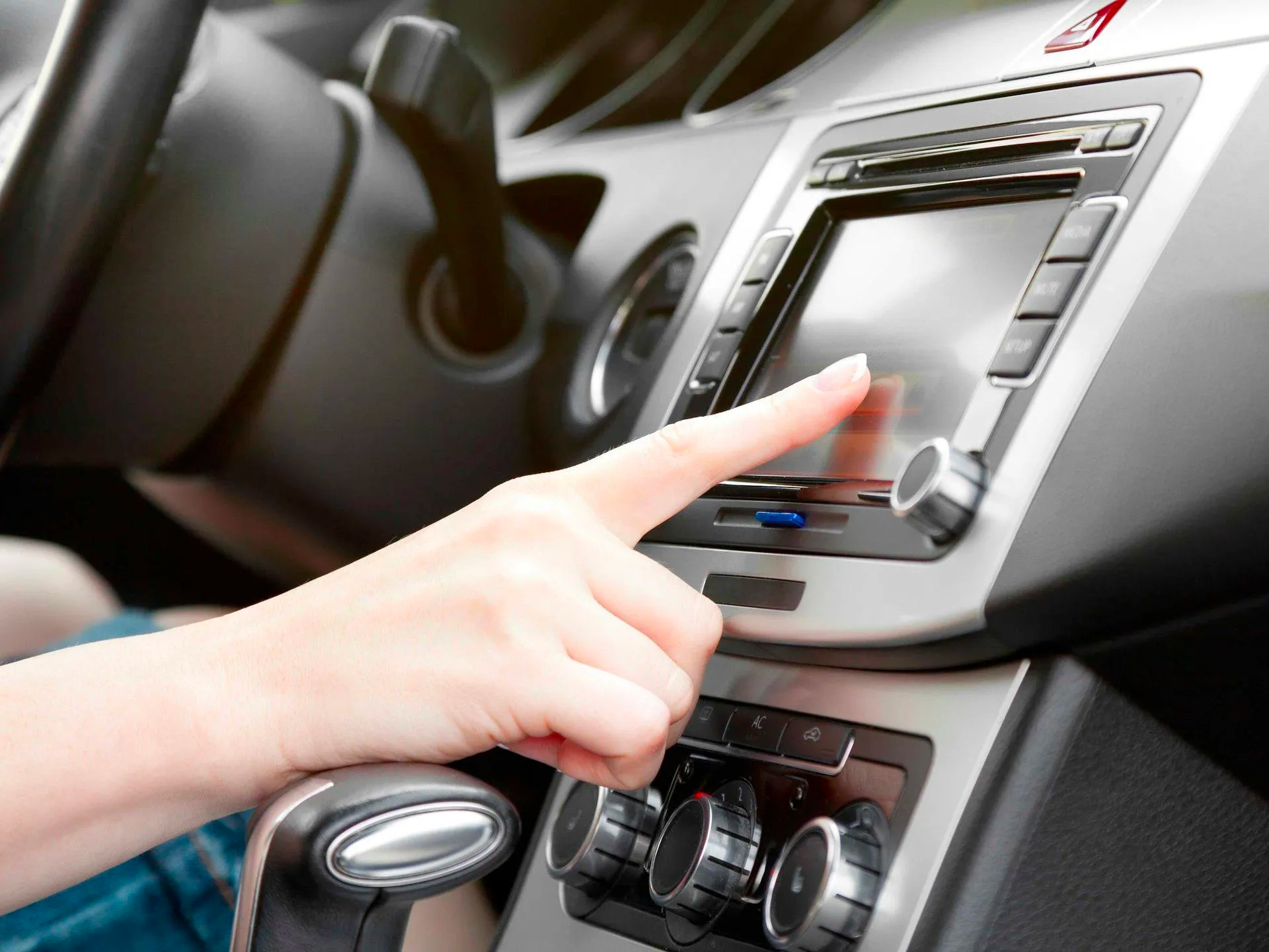 A person is pressing a button on a car radio