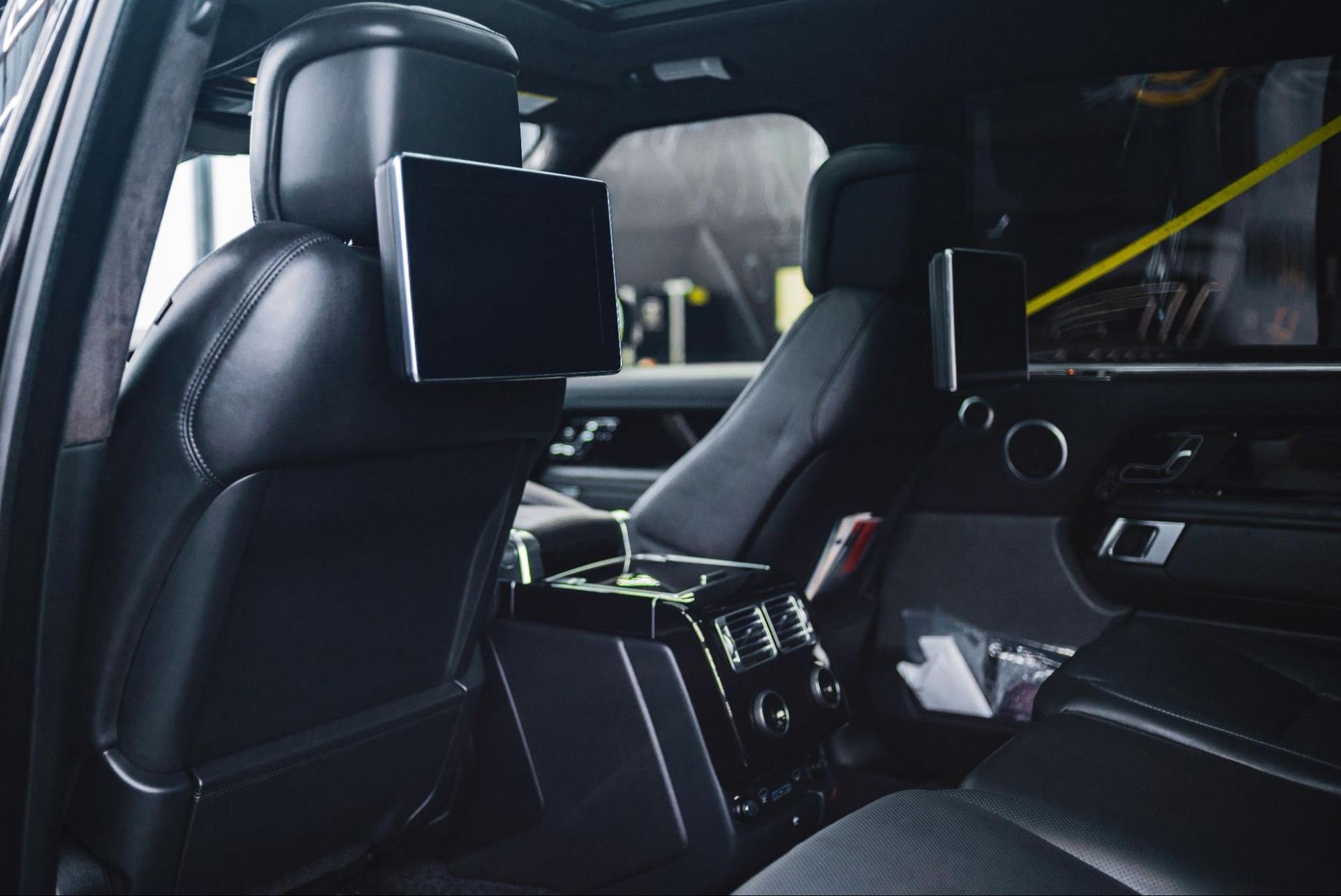 The back seat of a car with two headrest monitors.