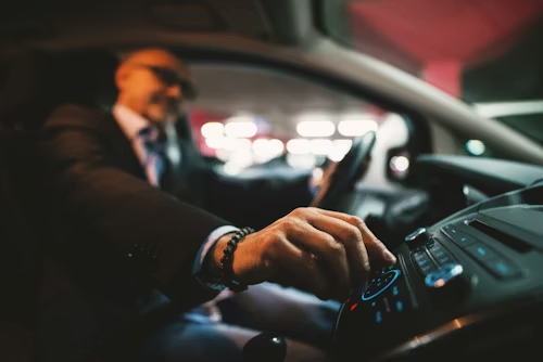 Person in suit adjusting car radio dial at night.
