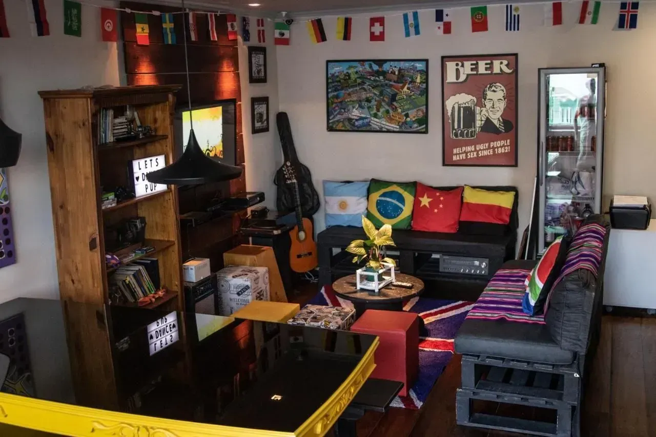Sala de estar aconchegante com bandeiras coloridas, sofá, TV, mesa de centro e obras de arte na parede.