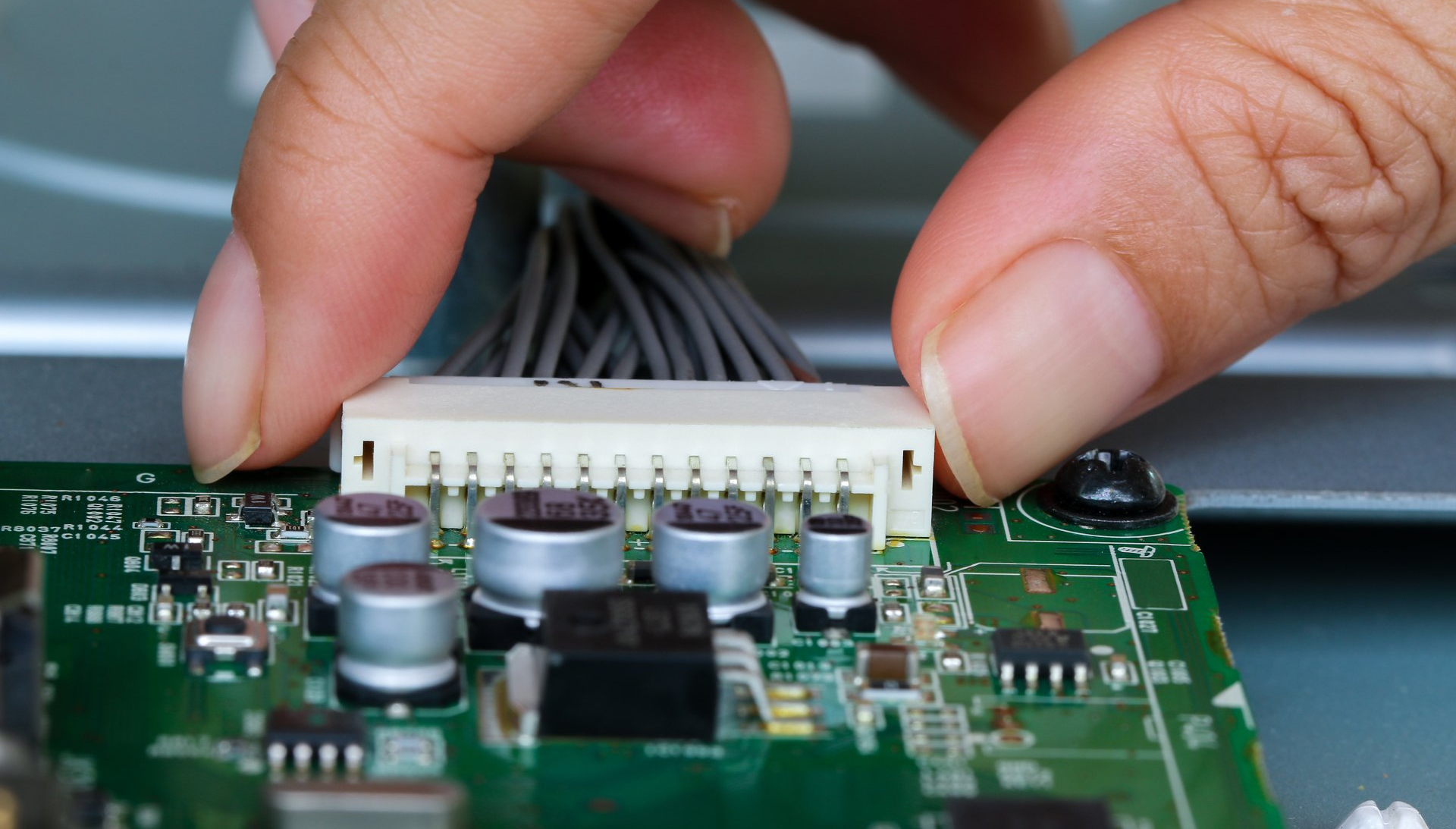 men installing a connector to electronic PCB board