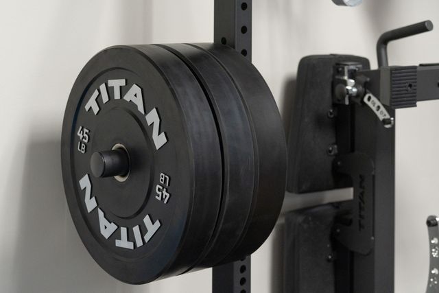 Titan weight plates loaded on a barbell in a gym rack.