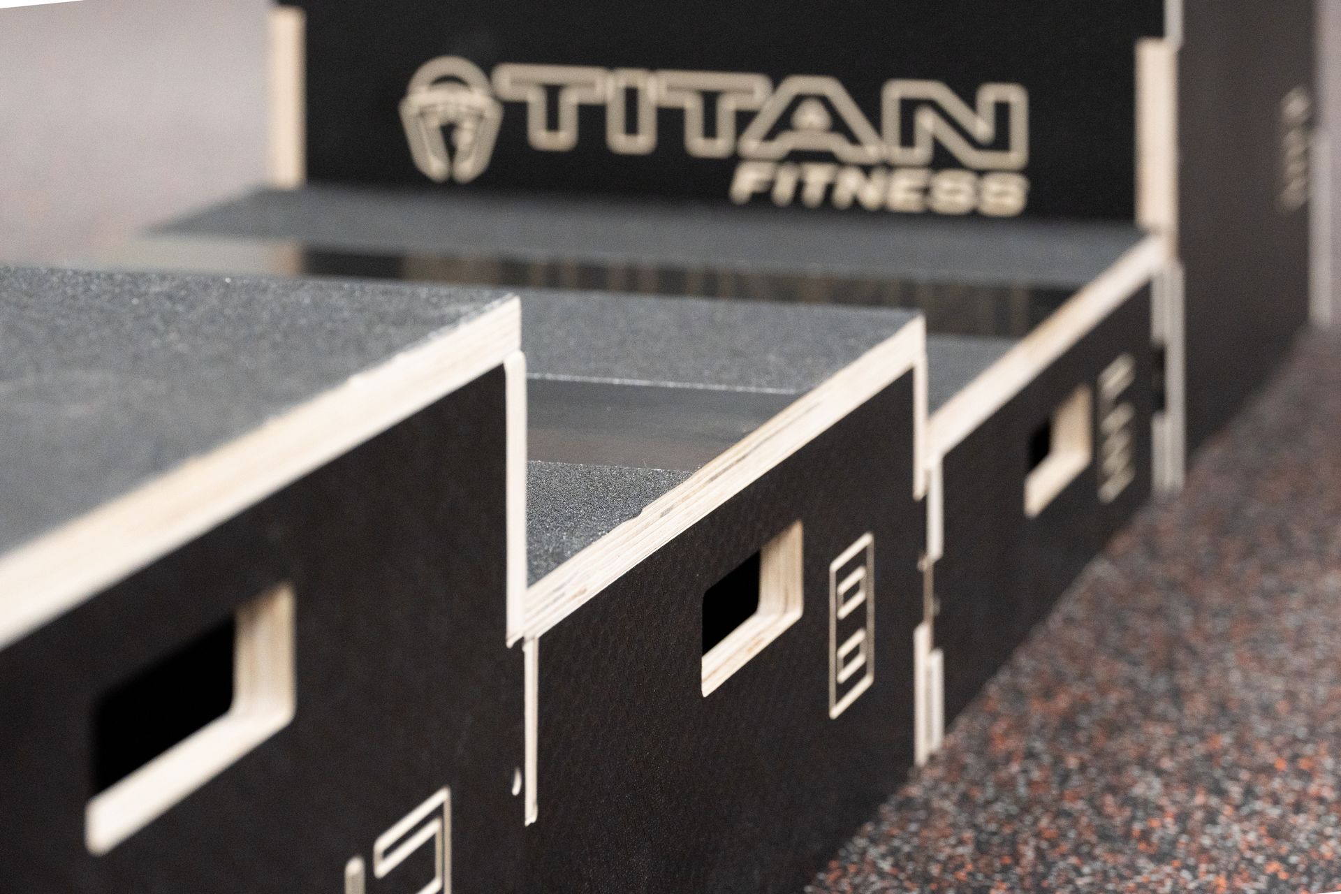 Stacked black fitness plyometric boxes with white trim, labeled “TITAN FITNESS,” in a gym setting