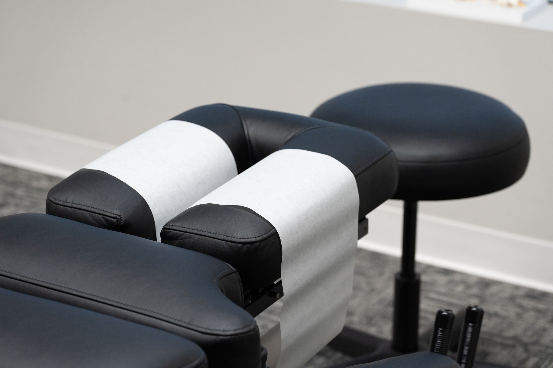Black-and-white padded leg supports on a treatment table in a clinic room
