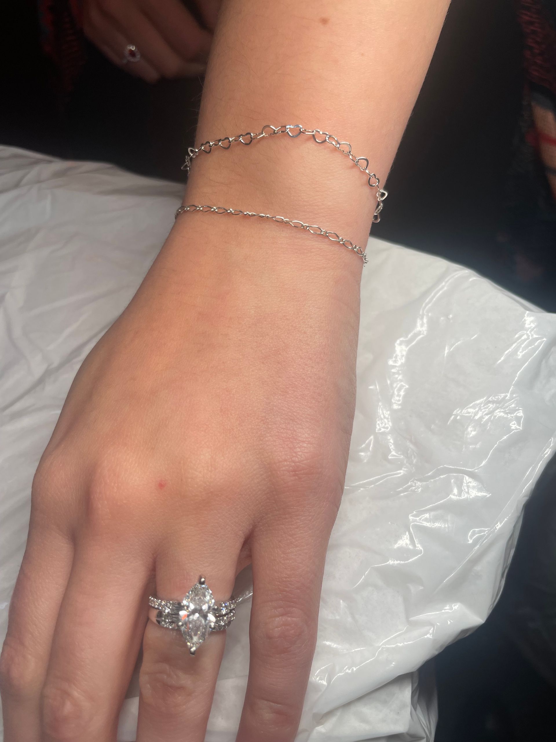 A woman is wearing a bracelet and a ring on her wrist.