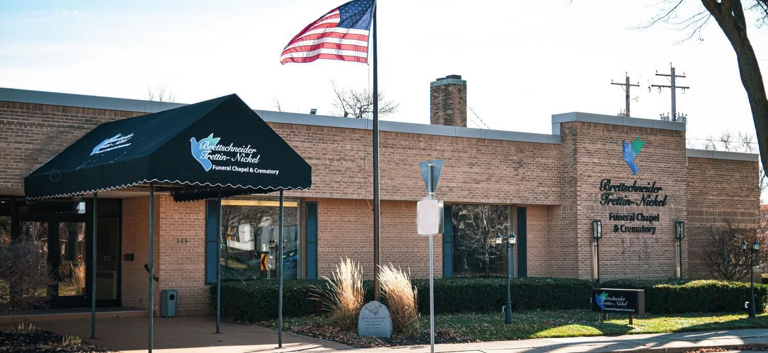 Brick building entrance with awning and U.S. flag, likely a community or service office.