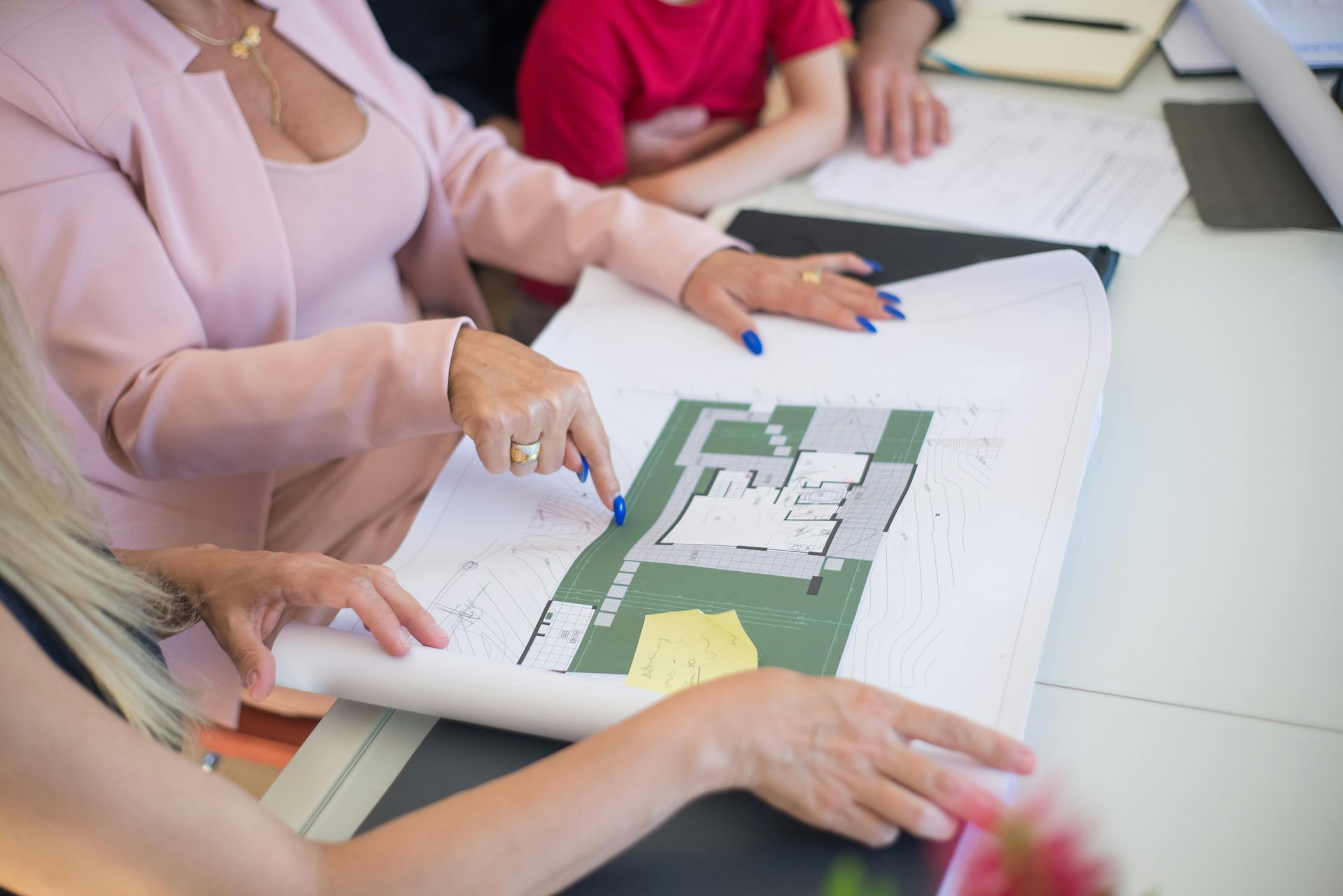 Hands pointing at a floor plan on a table during a meeting