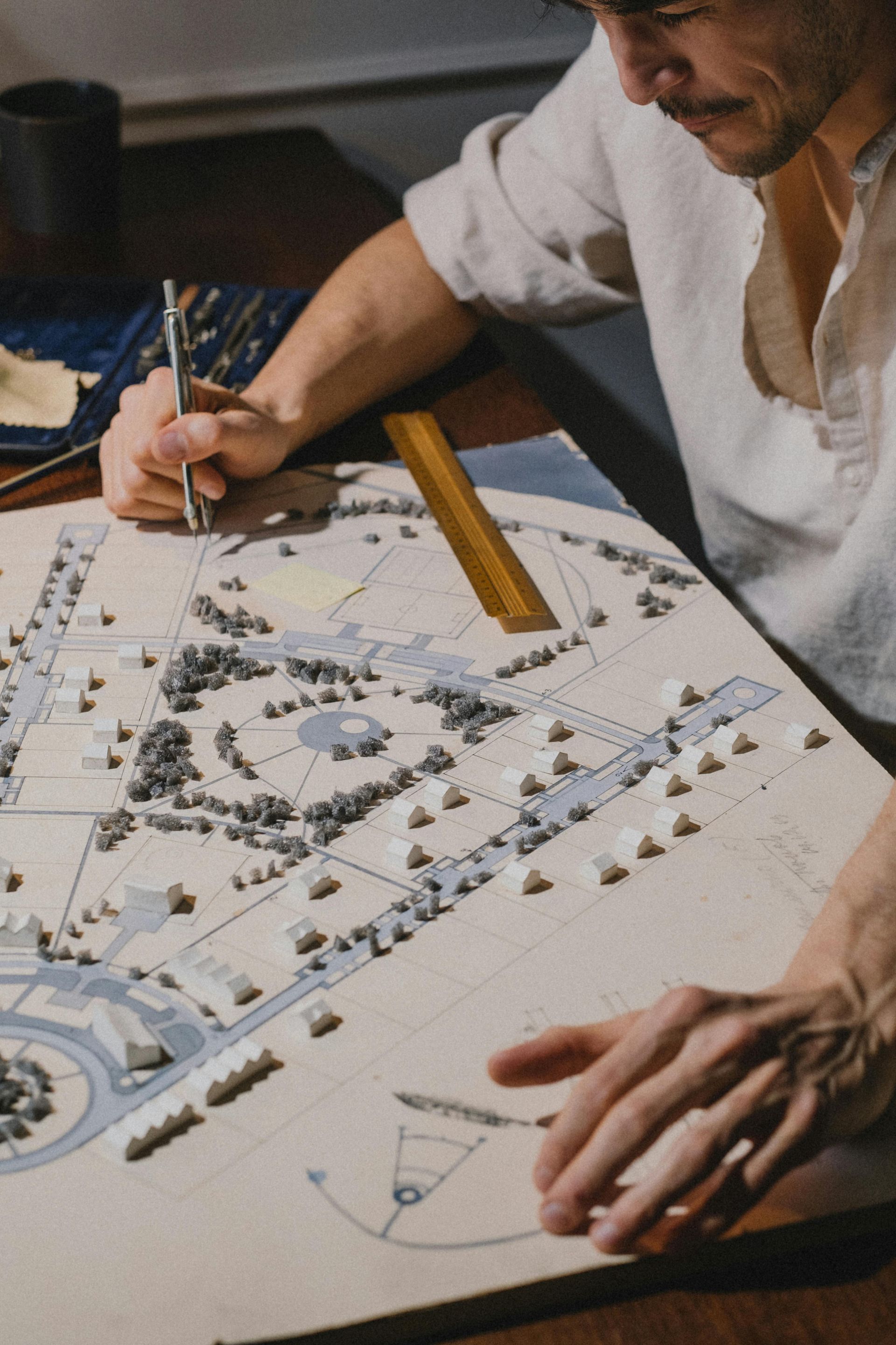 Person drawing a site plan on paper with a pencil and ruler at a desk