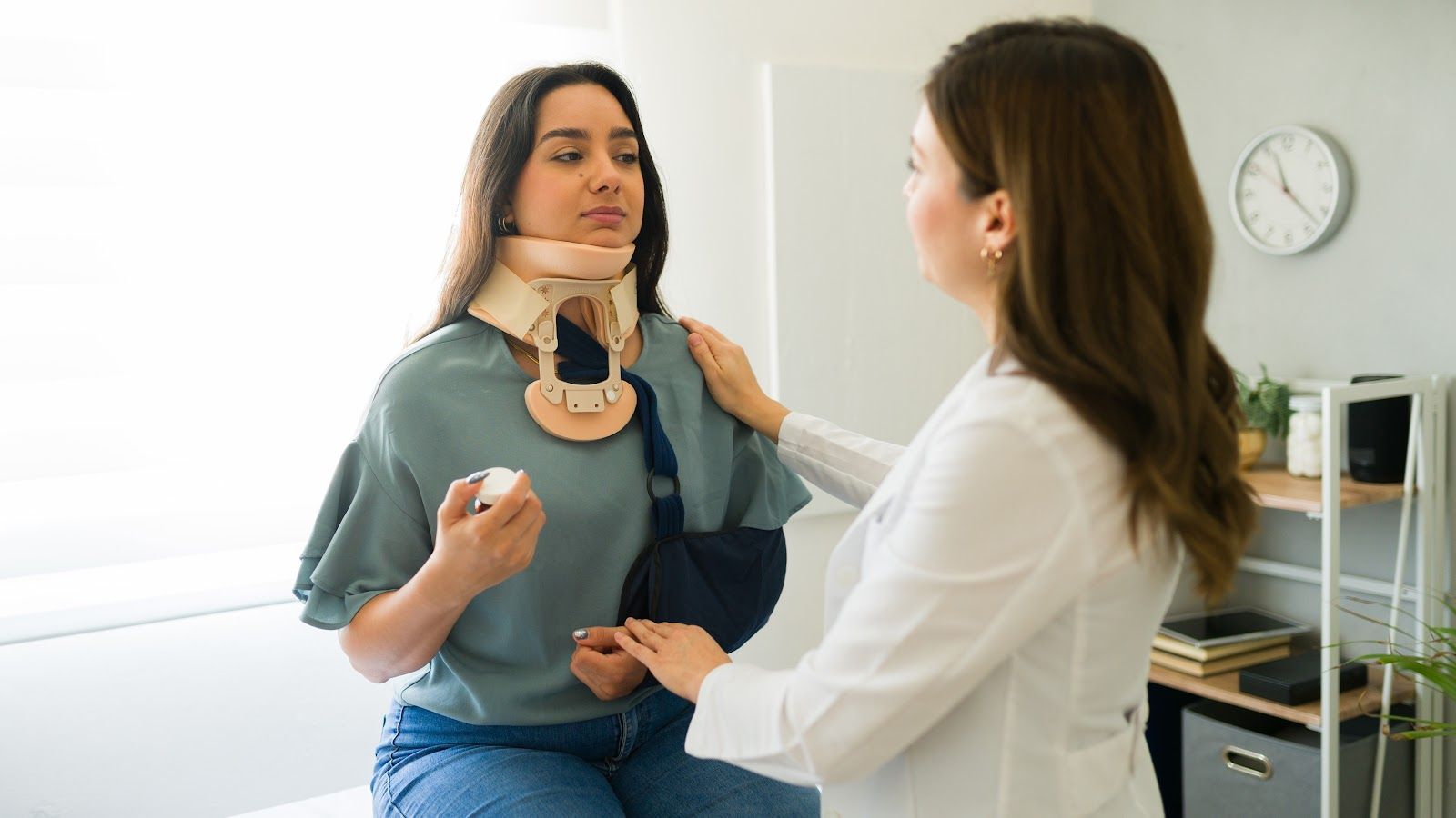 Doctor fitting a cervical collar on a patient in a clinic examination room