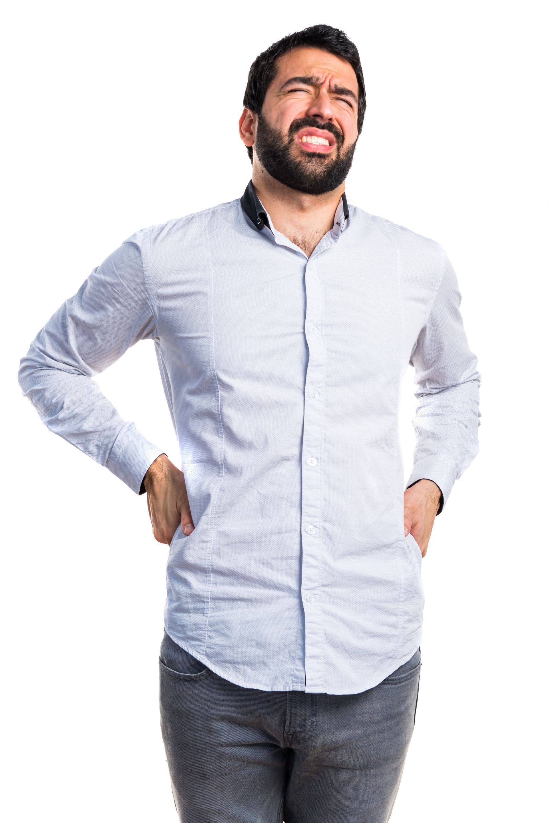 A man with a beard is holding his back in pain.