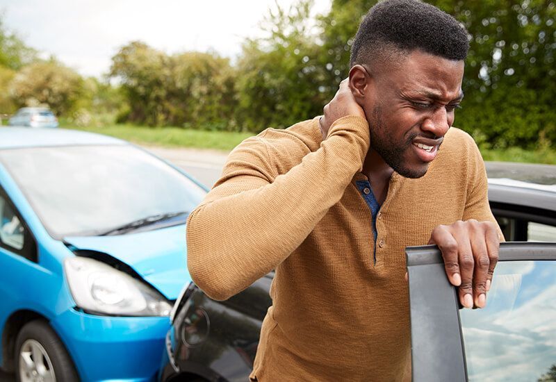 a man is holding his neck in pain after a car accident .