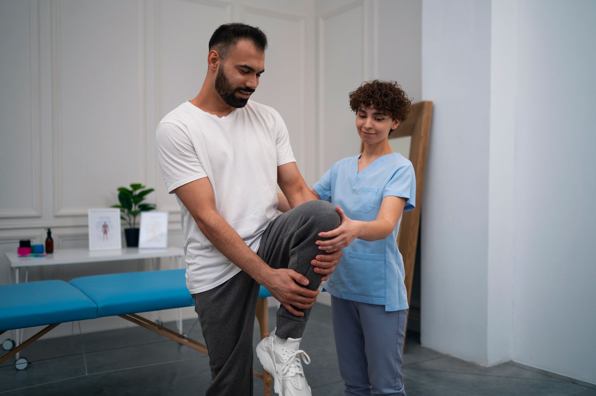 a woman is helping a man stretch his leg .