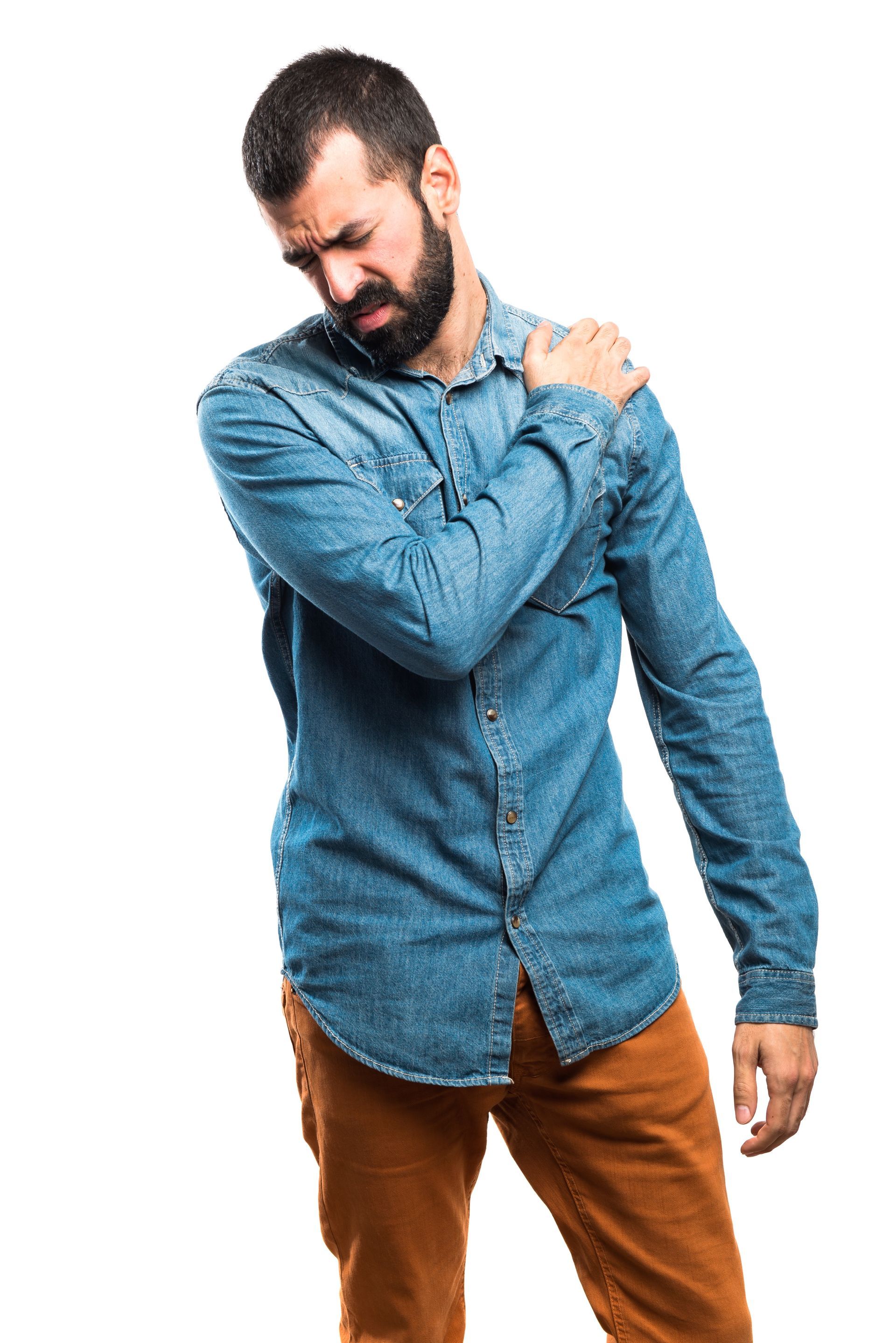 A man with a beard is holding his shoulder in pain.