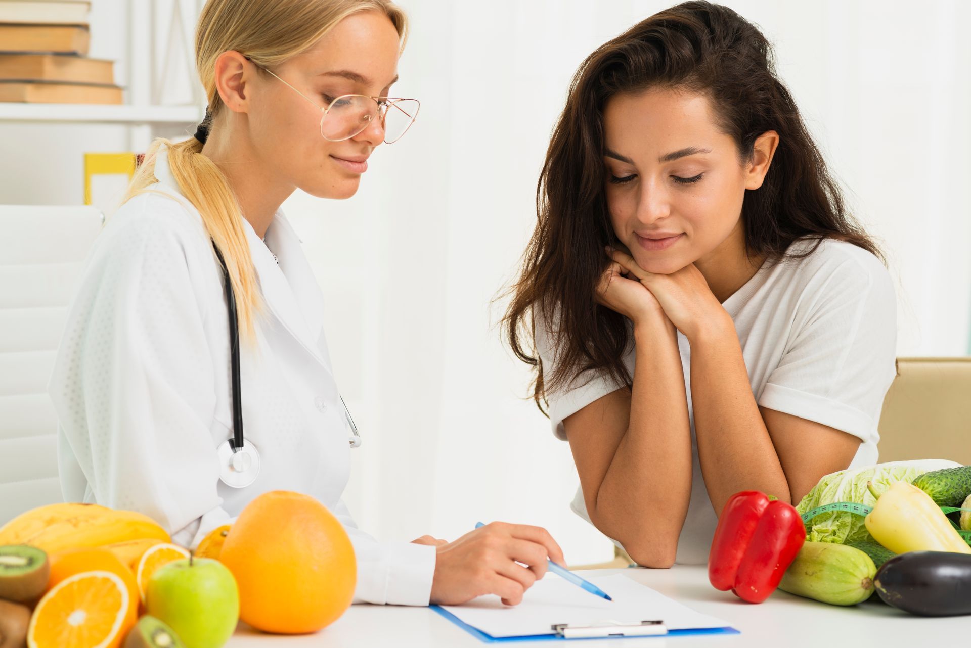 Dietitian reviewing a meal plan with a client beside fresh fruits and vegetables