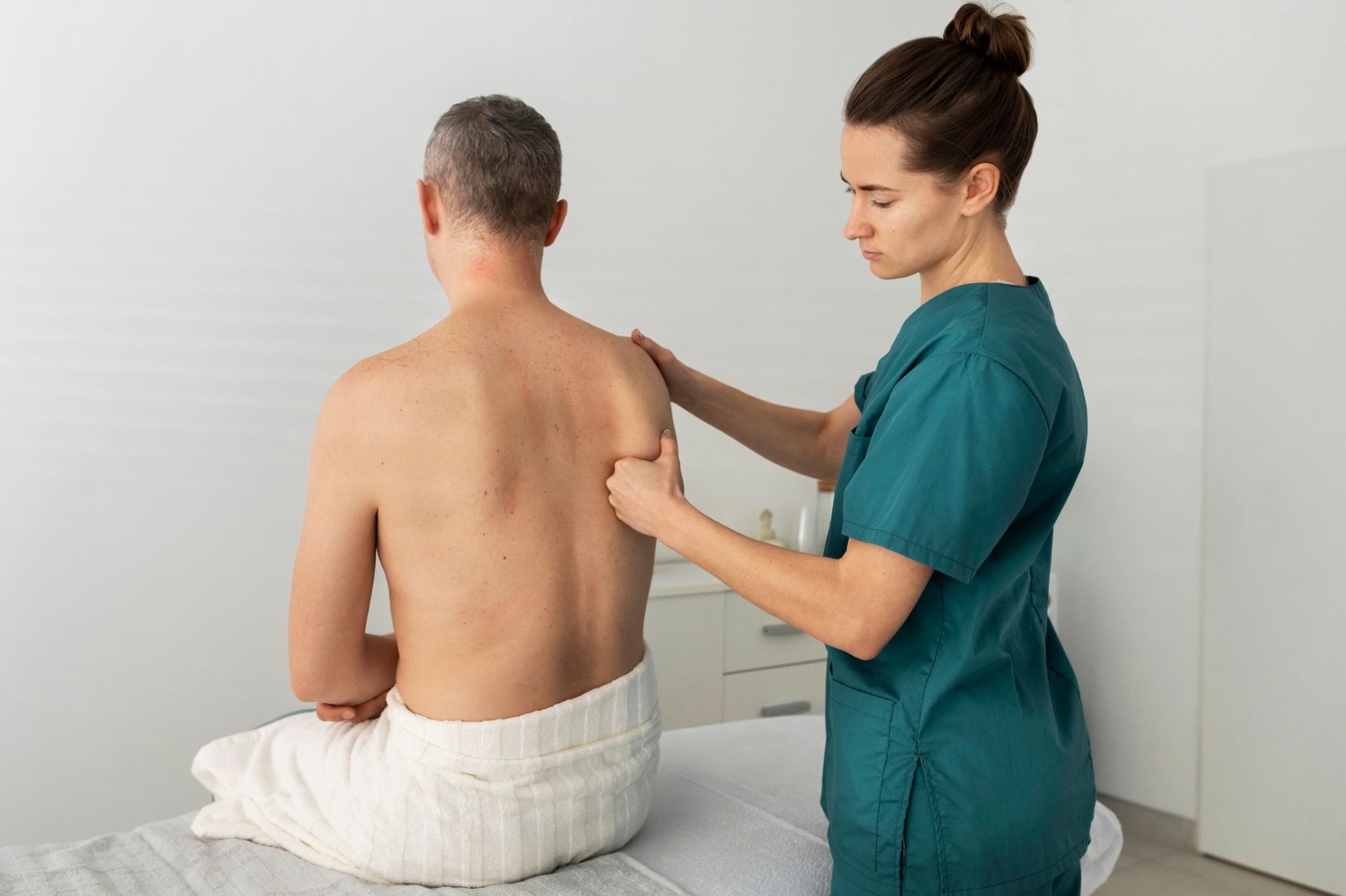 Therapist examining a patient’s back in a clinic room