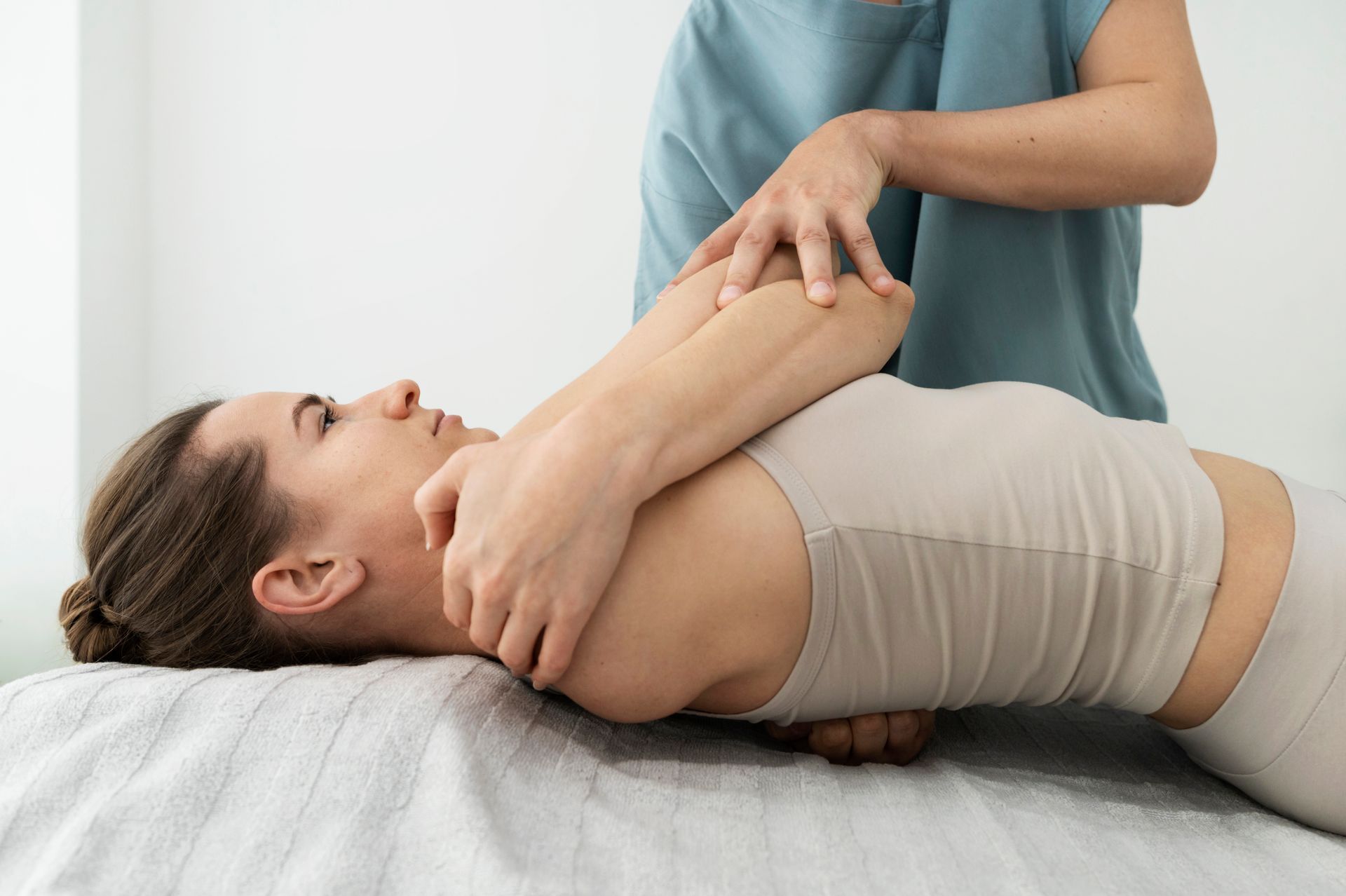 Physical therapist stretching a patient’s arm on a treatment table in a clinic