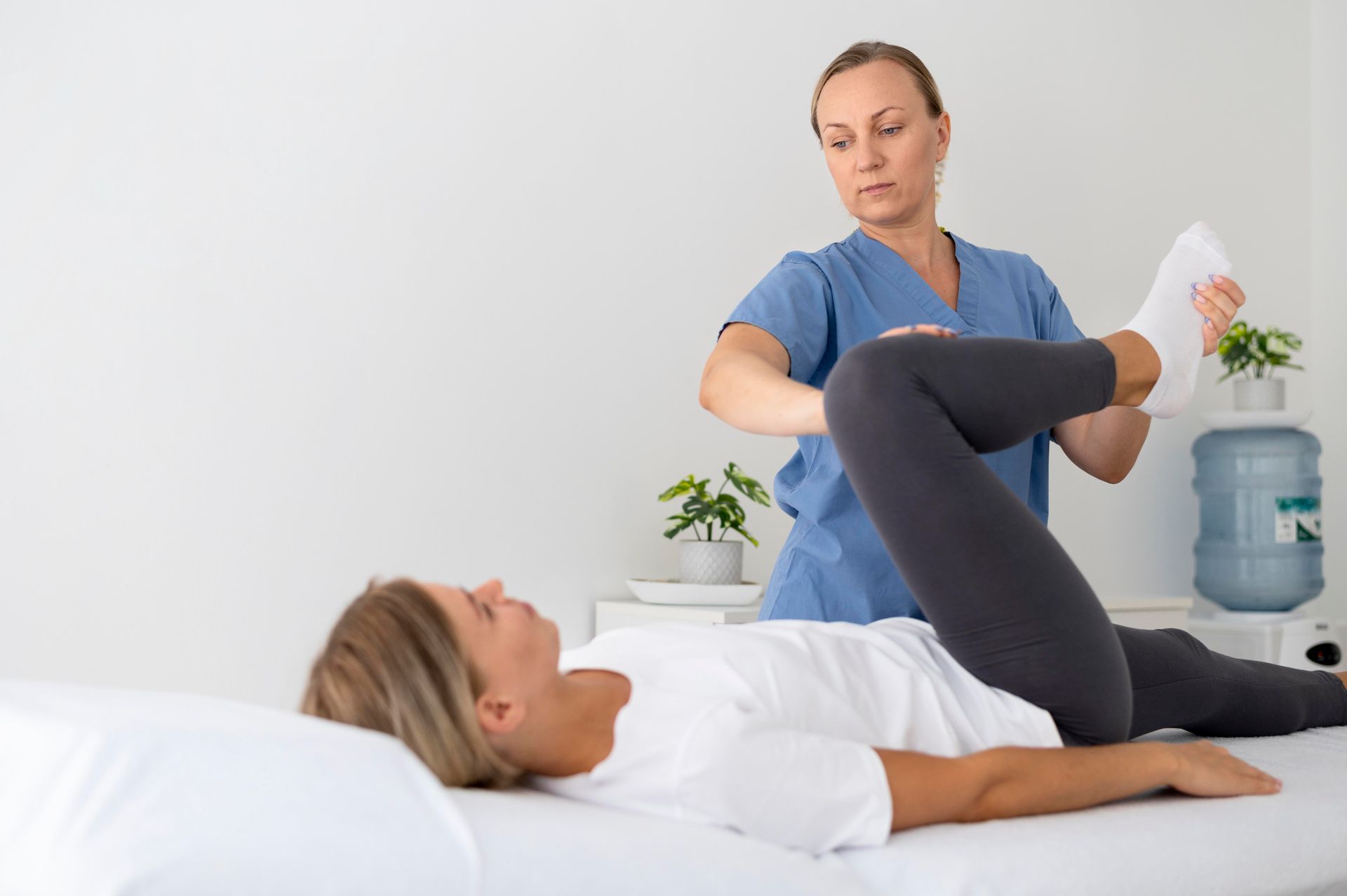 Physical therapist stretching a patient's leg on a treatment table in a bright clinic