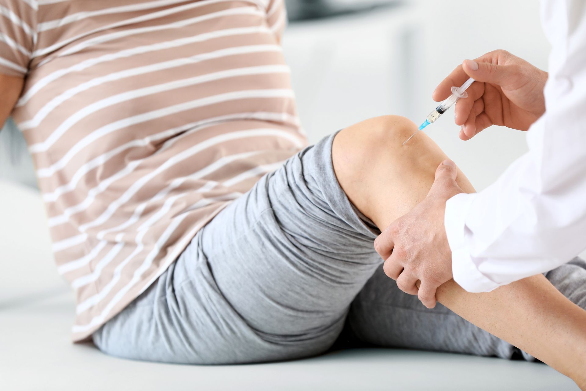 Healthcare worker giving an injection to a patient’s leg in a clinic