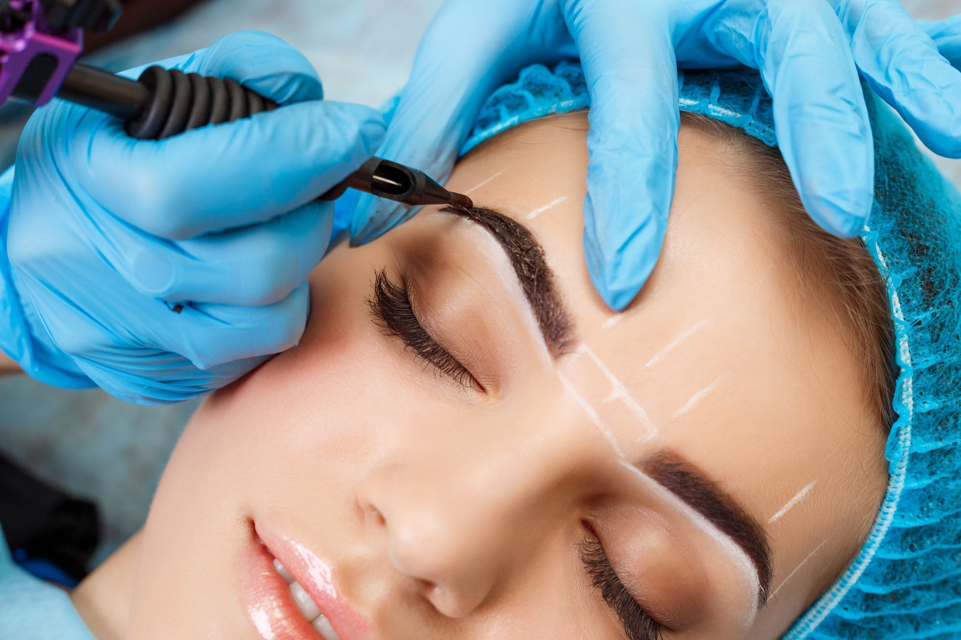 Cosmetic eyebrow treatment with gloved hands applying brow makeup to a woman’s closed eye