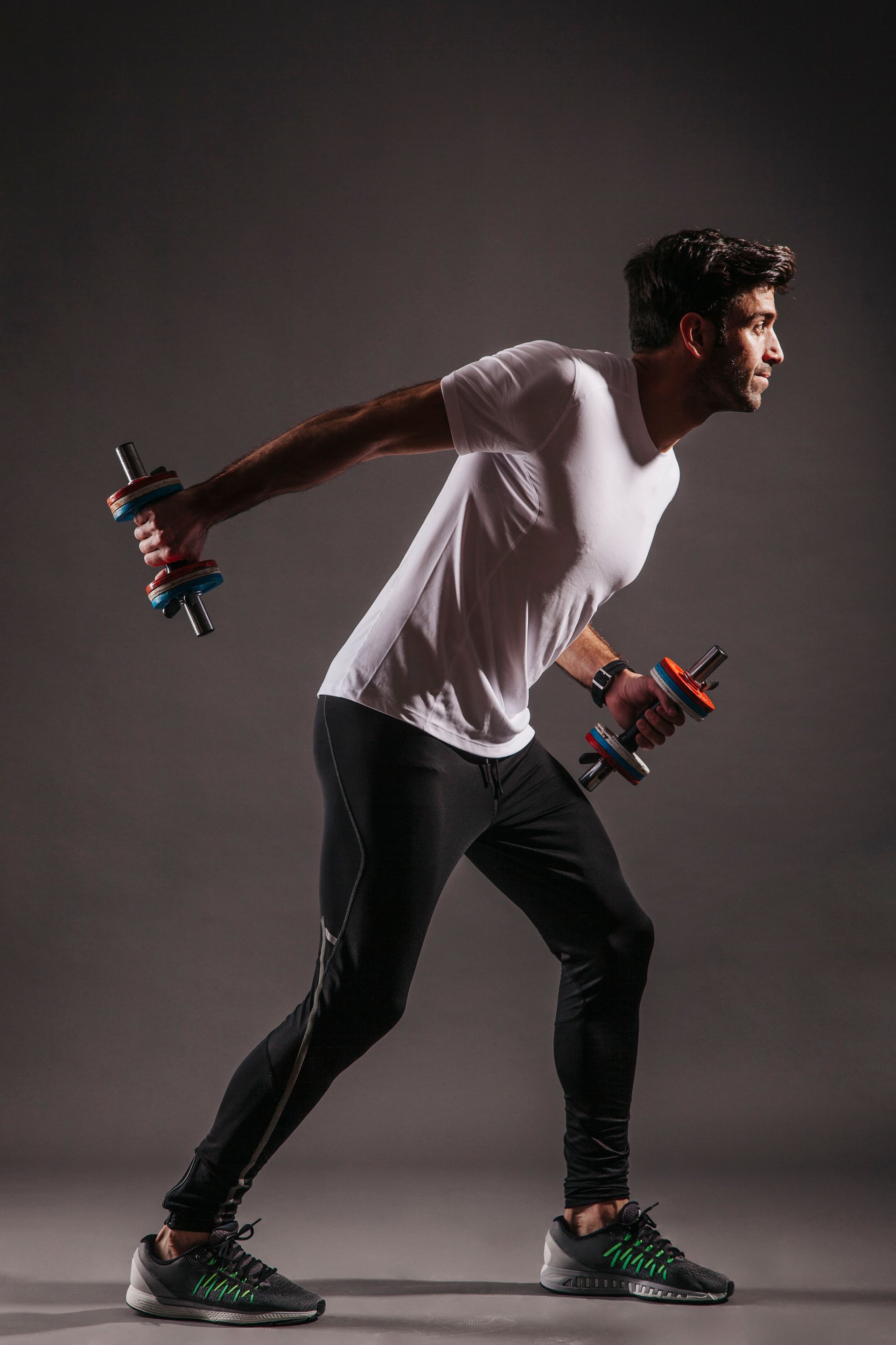 A man is holding a pair of dumbbells in his hands.